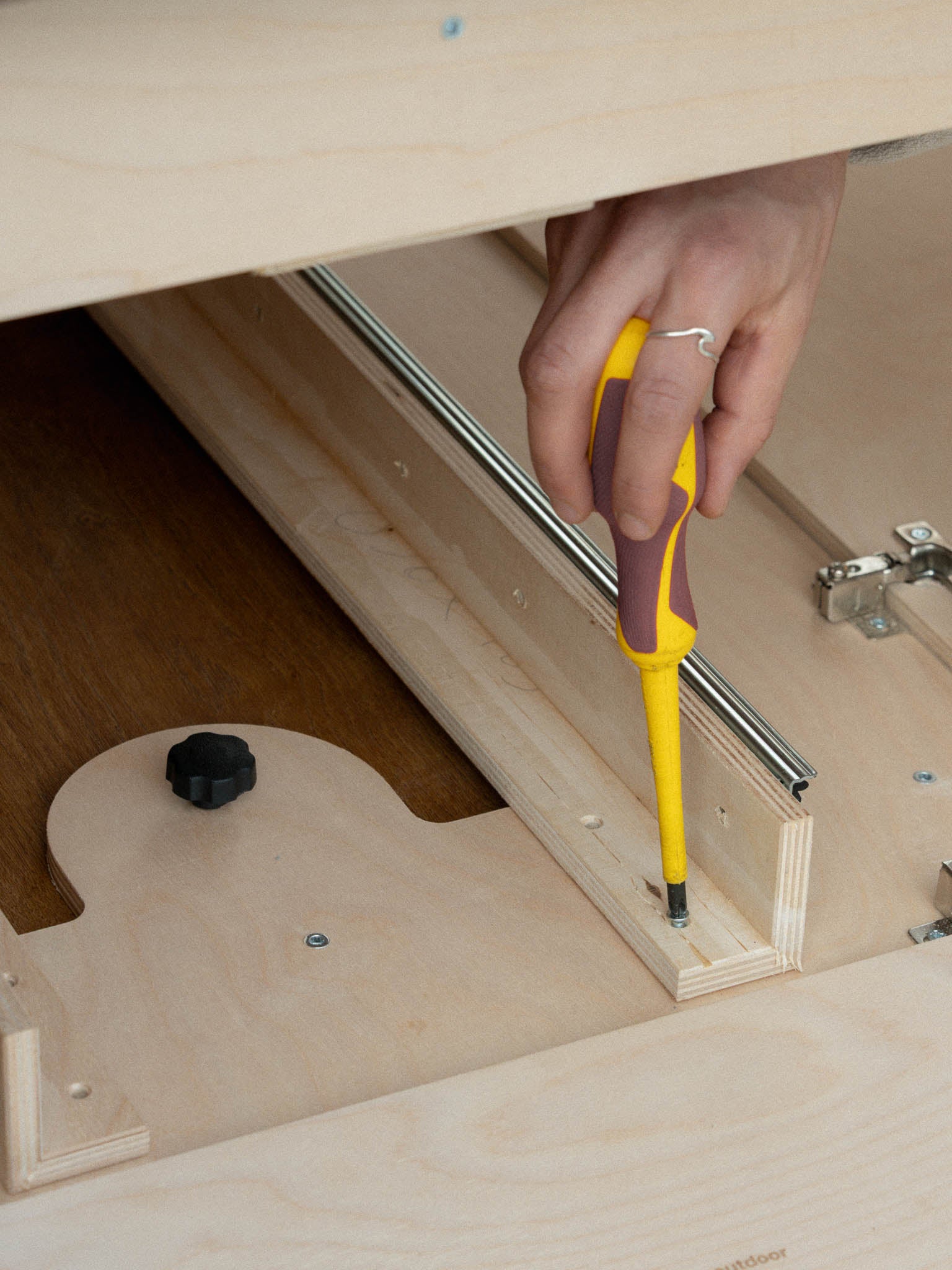 Dettaglio di cacciavite che fissa il piano estraibile laterale del Letto Nom Outdoor, sistema modulare per camperizzazione van con accesso laterale allo stivaggio