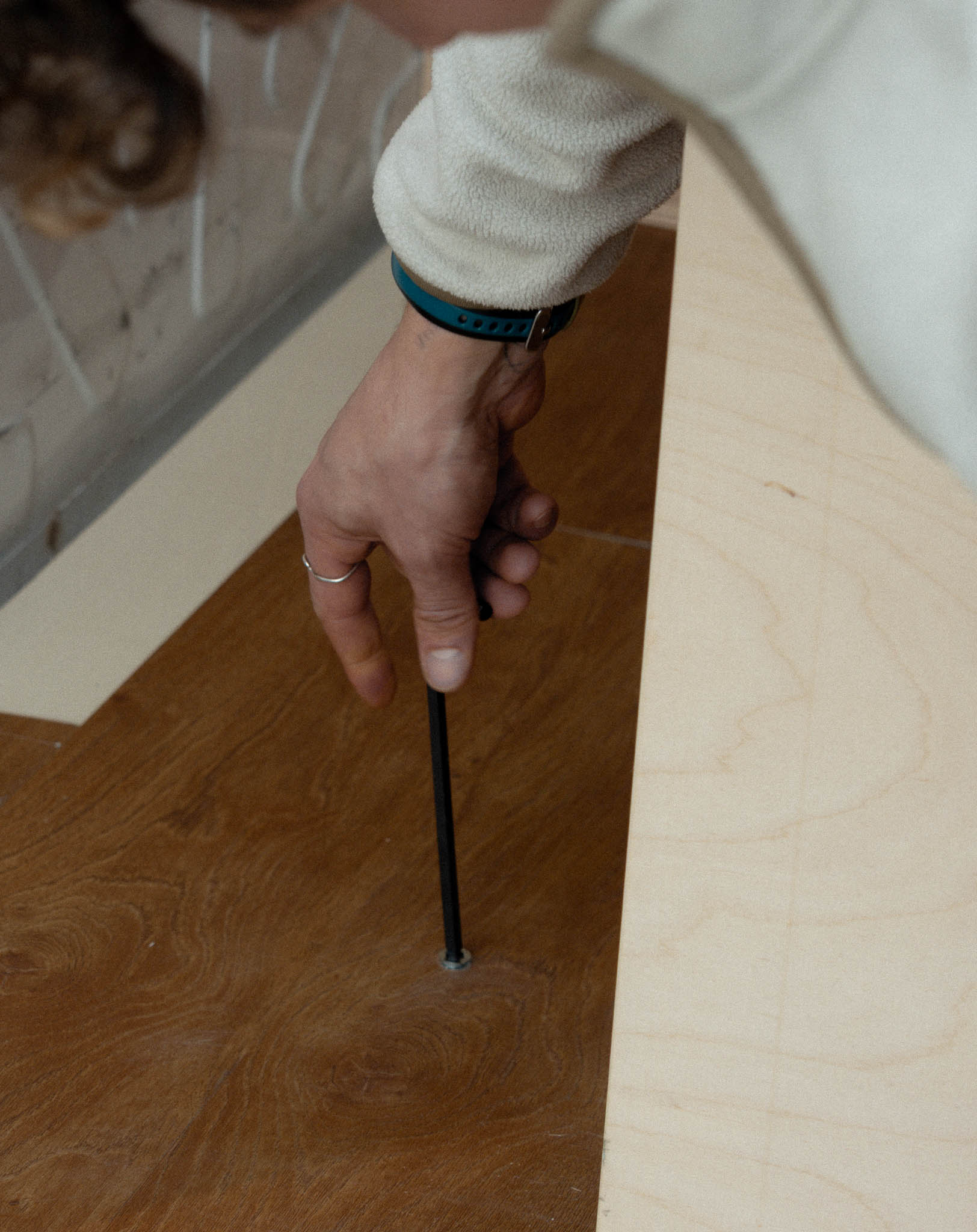 Mano che inserisce la bussola nel pianale del furgone per il sistema di fissaggio Nom Outdoor, soluzione sicura e modulare per camperizzazione van.