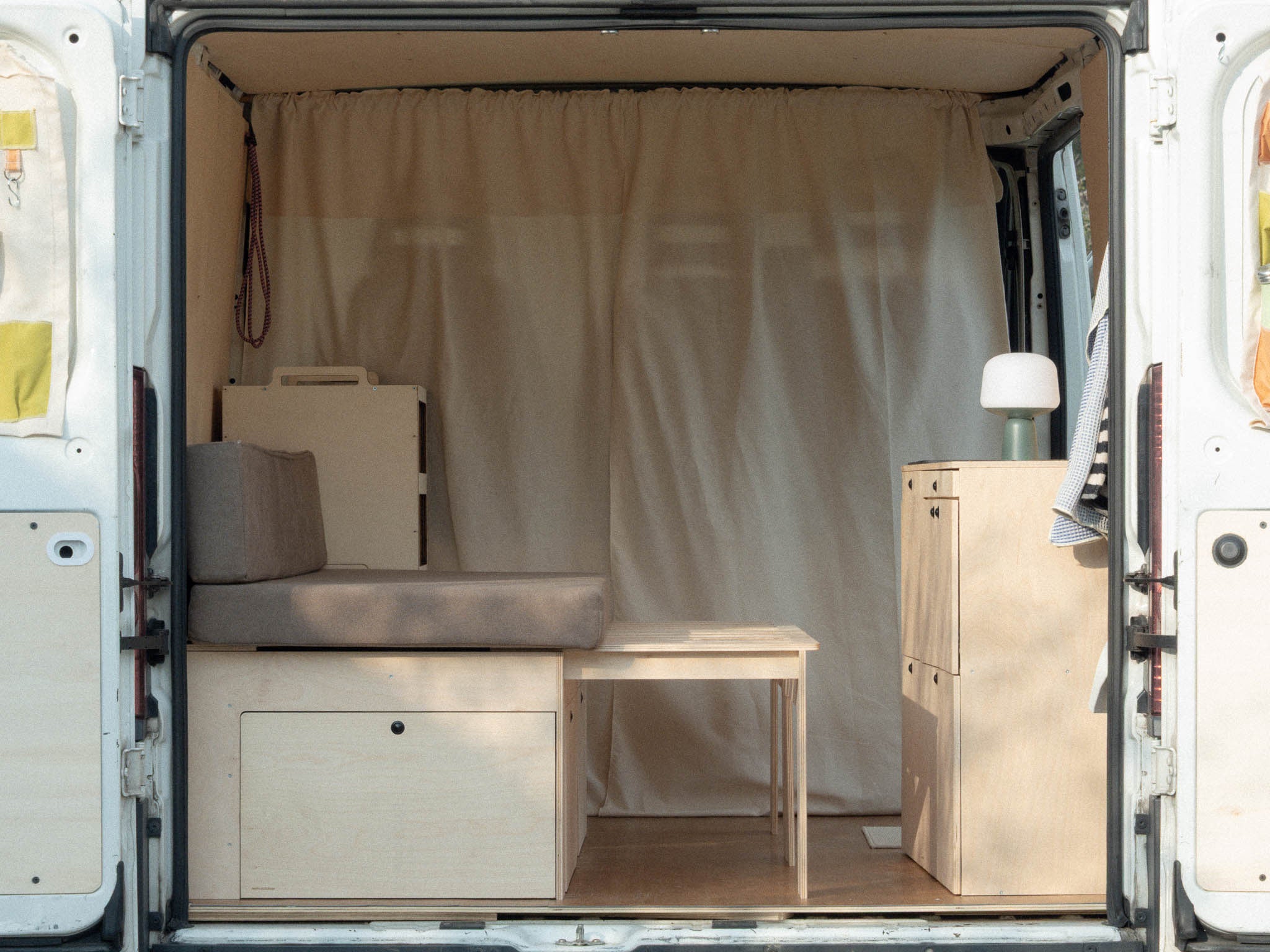 Letto Nom Outdoor in trasformazione da divano a letto con pettine allungato, sistema modulare per camperizzazione van con configurazione giorno e notte