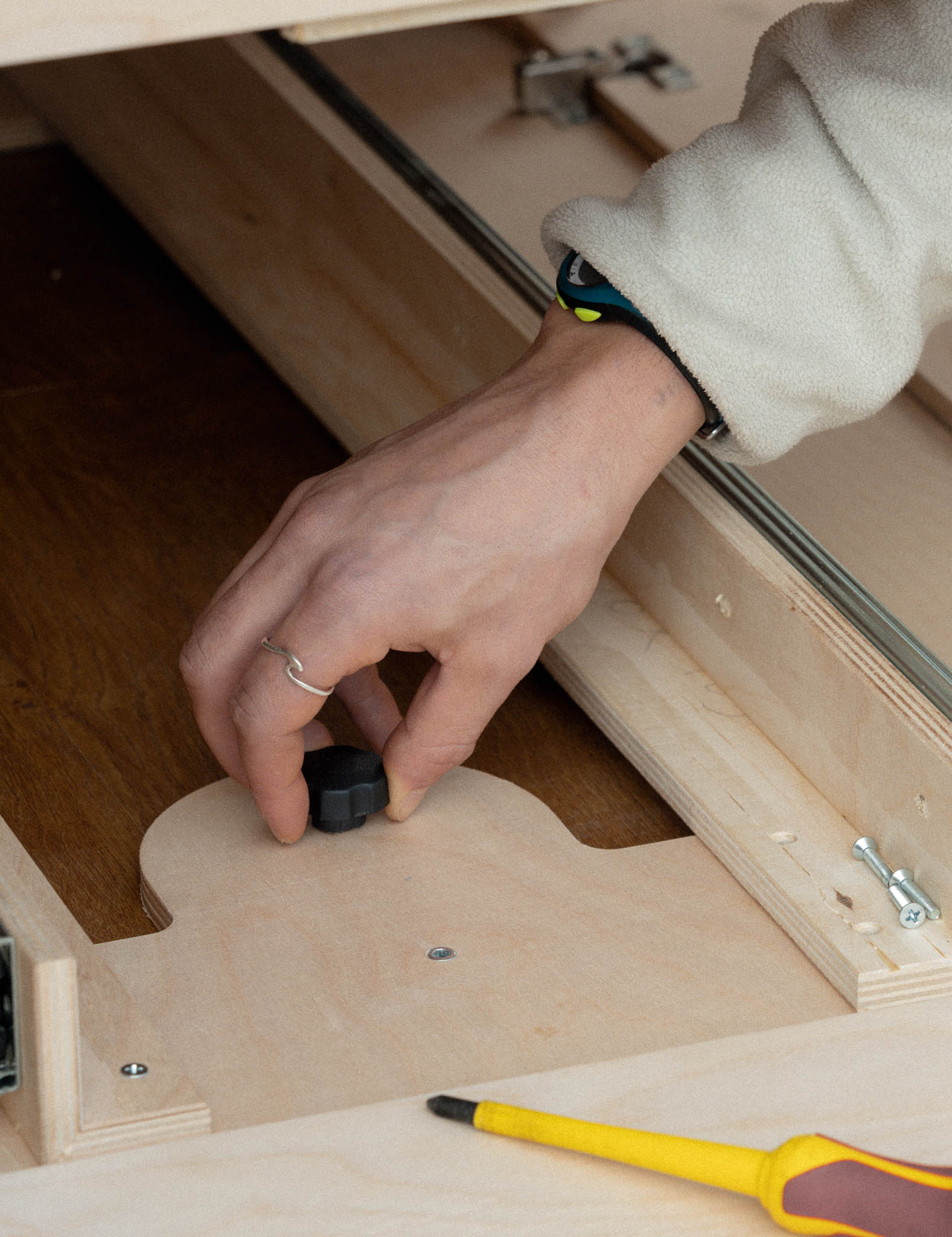 Mano che installa la vite a farfalla del sistema di fissaggio Nom Outdoor per moduli camperizzazione van, soluzione modulare e reversibile senza modifiche permanenti