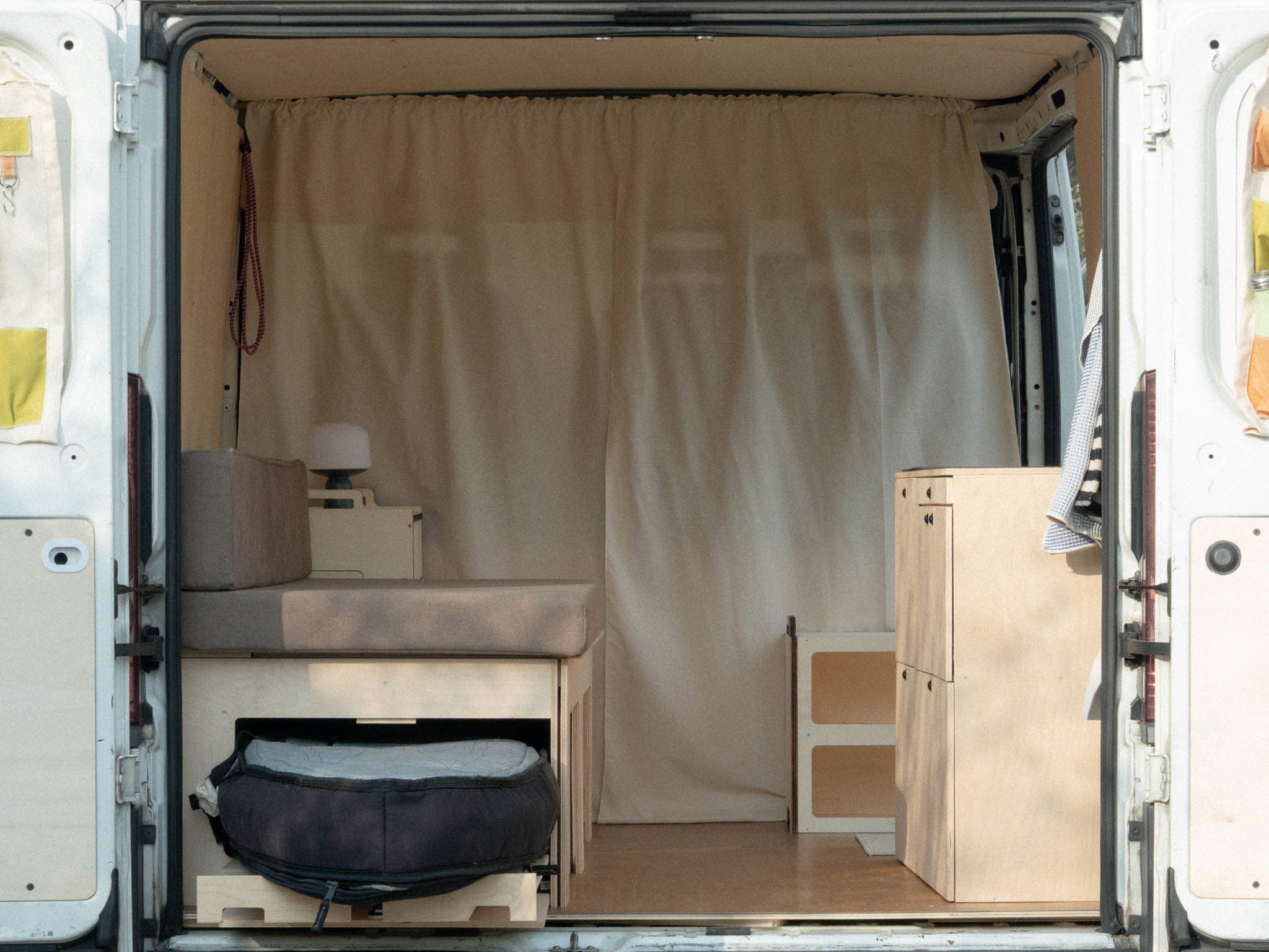 Nom Starter Kit con letto modulare e piano estraibile laterale che ospita una tavola da surf, soluzione per camperizzazione van ideale per surfisti e sport outdoor