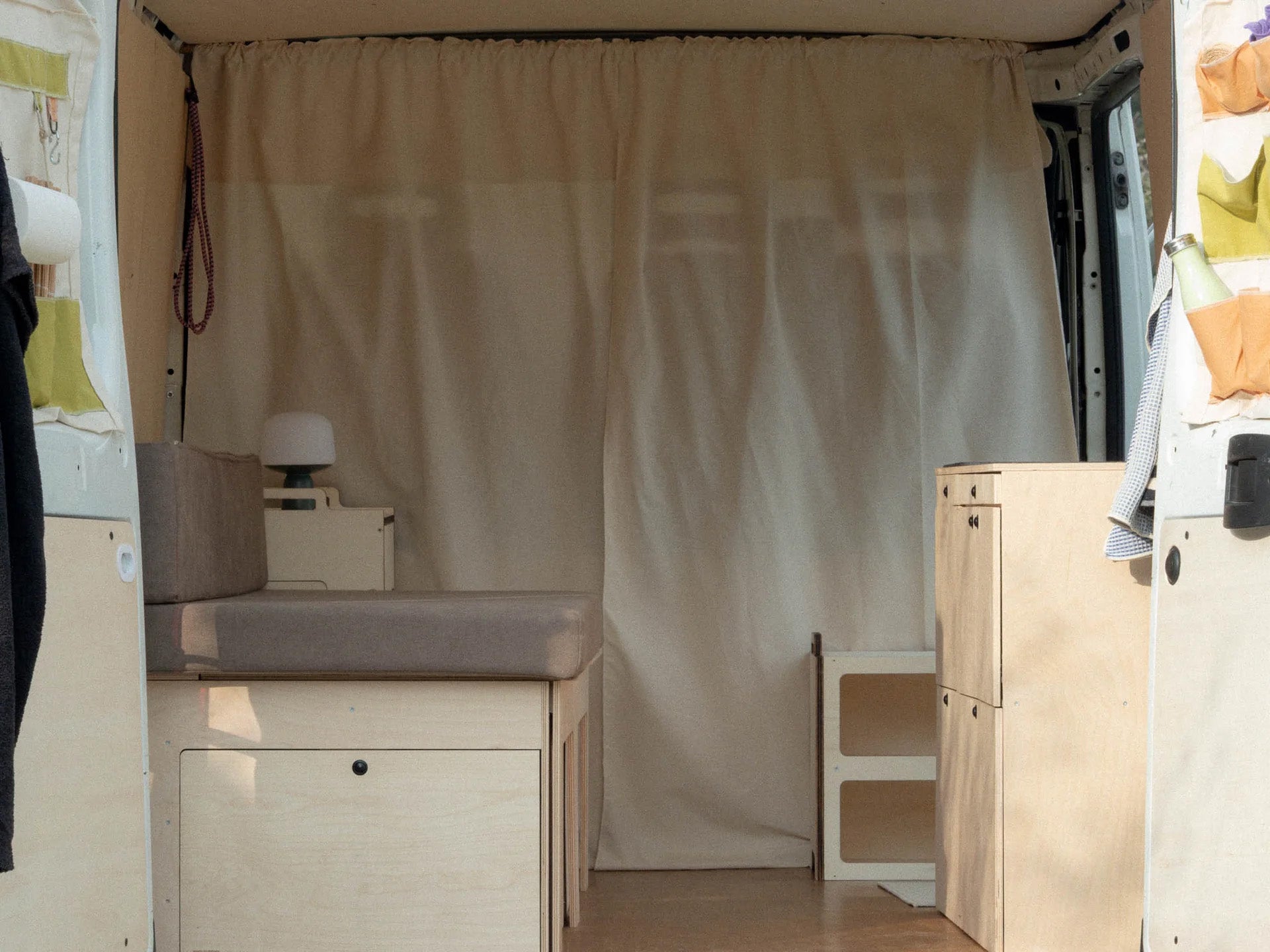 Nom Total Kit con letto chiuso in configurazione giorno, sistema modulare per camperizzazione van compatta e ottimizzazione dello spazio interno.